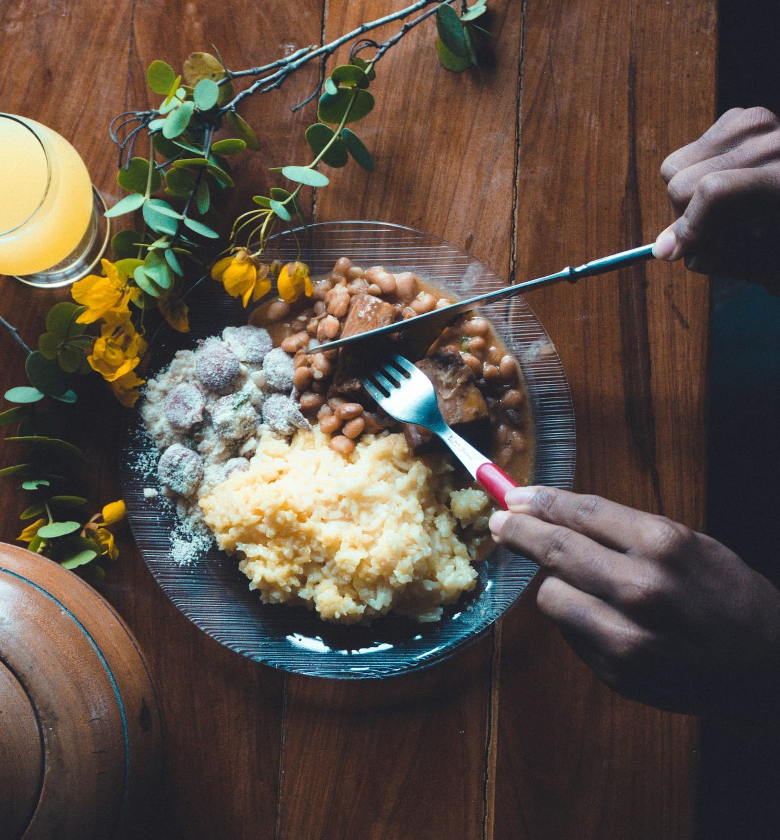 Prato de arroz, feijão e carne servido em mesa de madeira, visto de cima